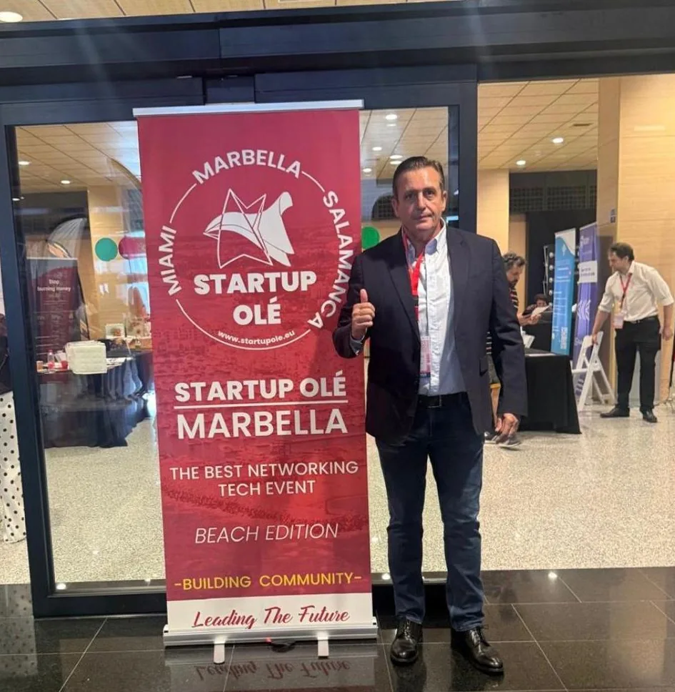 Ignacio Campoy con el pulgar arriba junto al panel de Startup Olé Marbella